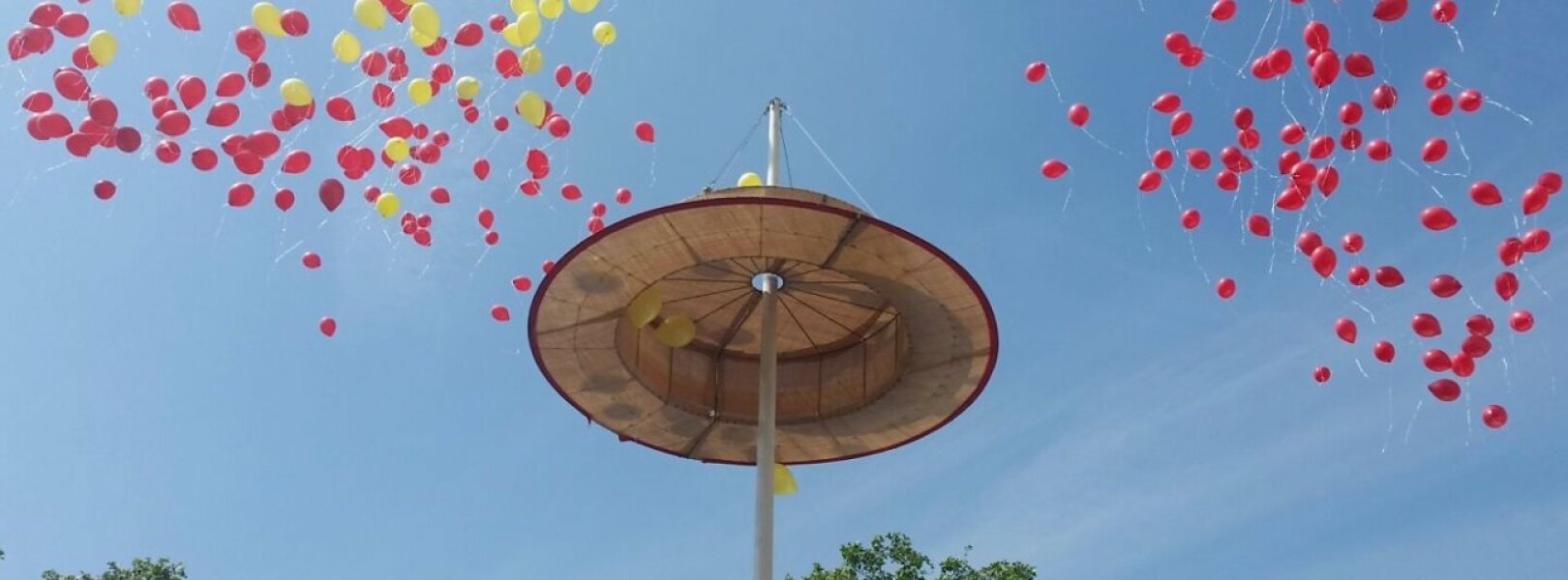 Strohut vor blauem Himmel mit roten Luftballons