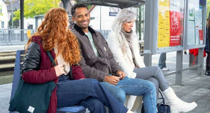 Fahrgäste sitzen auf einer Bank im Bahnhof